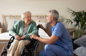 A senior resident and a caregiver sit together, discussing a care plan at a table with papers and a pen.